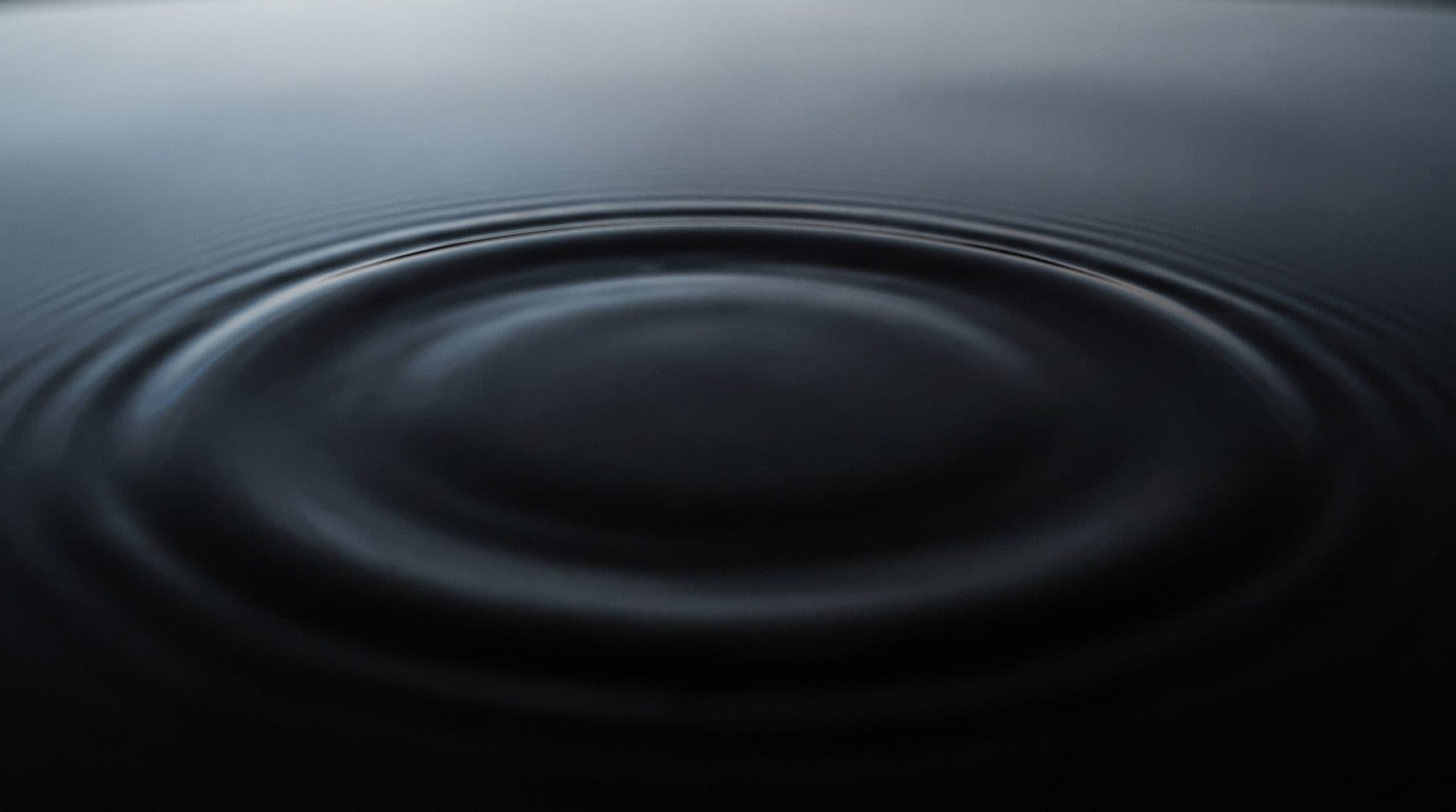 Stille, dunkle Wasseroberfläche mit feinen Ringen